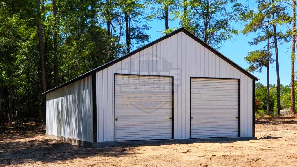Gray metal garage with two roll-up doors surrounded by trees