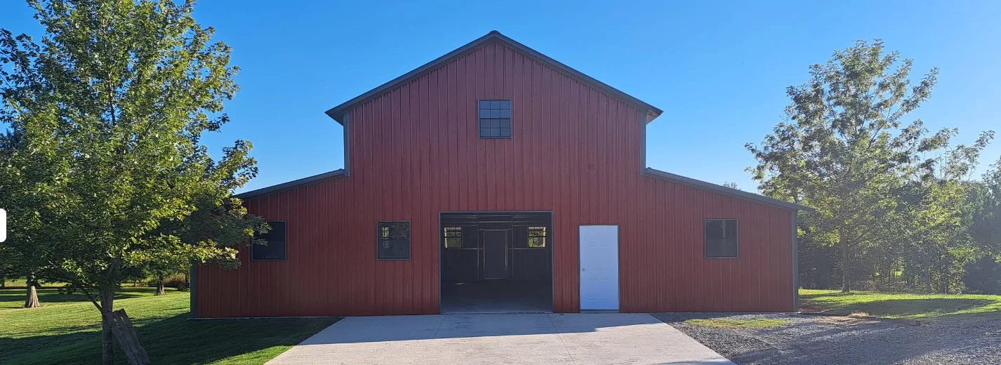 Red barn with a clear blue sky and trees nearby