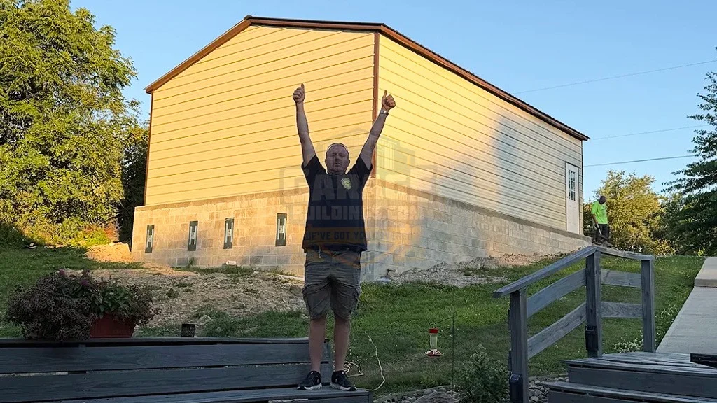 Person celebrating with arms raised in front of a partially completed building