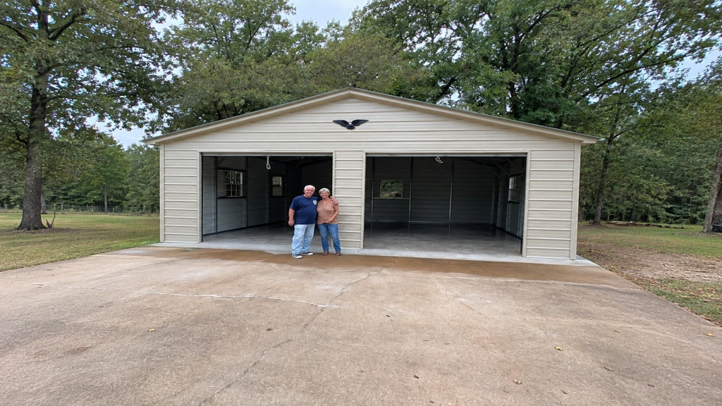 Two men standing in front of a large garage with open doors