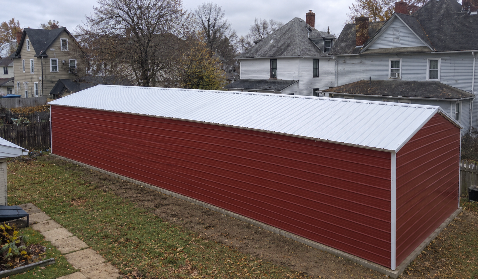 Long red barn with a white roof in a residential area